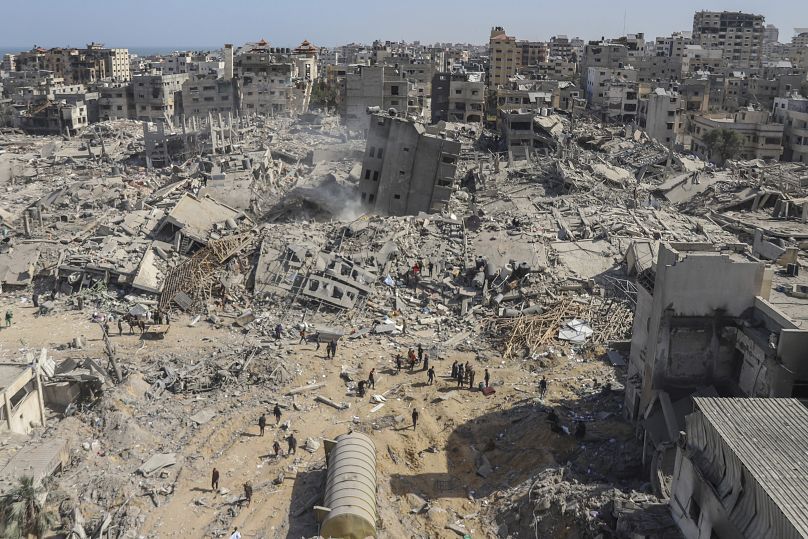 فلسطينيون يسيرون وسط الدمار الذي خلفه الهجوم الجوي والبري الإسرائيلي على قطاع غزة بالقرب من مستشفى الشفاء في مدينة غزة، في 1 أبريل/نيسان 2024