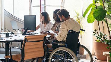 Team with a person with disability working in a office.