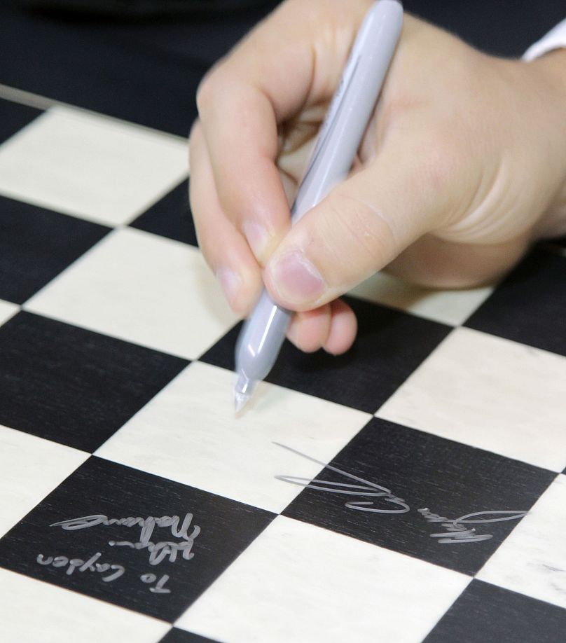 Grandmaster Magnus Carlsen signs a chess board at the Chess Club and Scholastic Center of St. Louis, Tuesday, Aug. 26, 2014 in St. Louis.