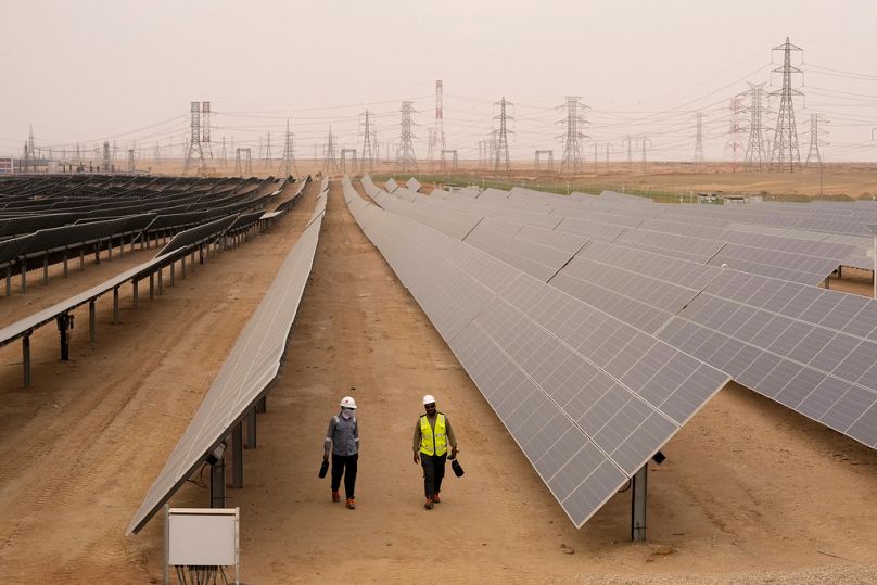 مهندسون يسيرون بجوار الألواح الشمسية في محطة للطاقة الشمسية في أسوان بمصر