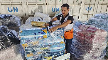 FILE - United Nations and Red Crescent workers prepare the aid for distribution to Palestinians at the UNRWA warehouse in Deir Al-Balah, Gaza Strip, on Monday, Oct. 23, 2023.