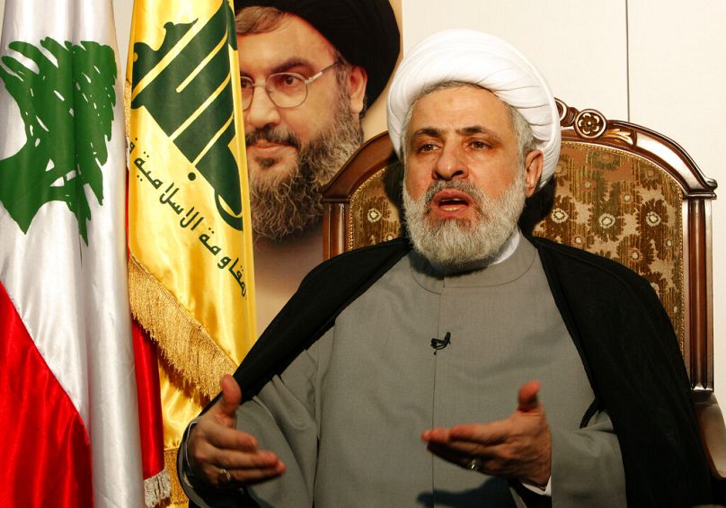  صورة أرشيفية لنائب الأمين العام لحزب الله نعيم قاسم وخلفه صورة الأمين السابق حسن نصر الله 