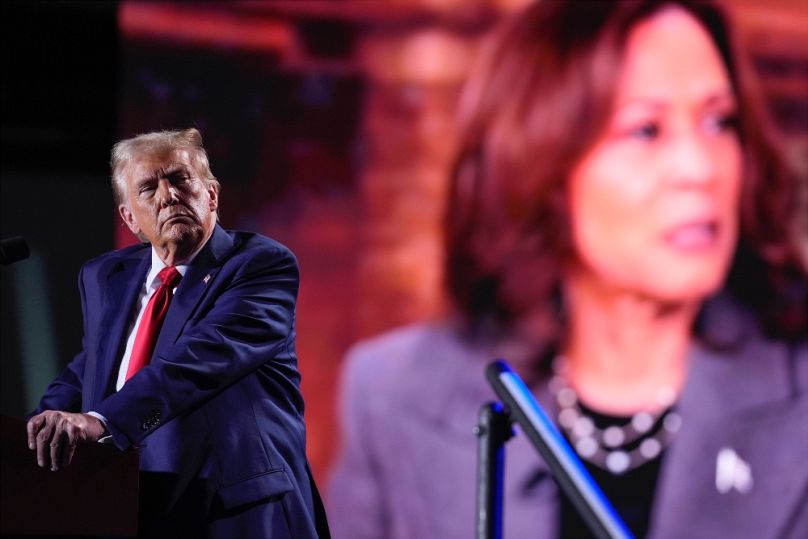 Donald Trump a kivetítőn nézi Kamala Harris fellépését egy detroiti kampányrendezvényen, 2024. október 18-án