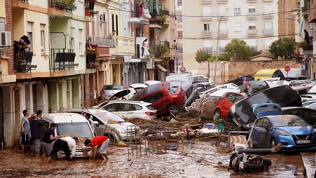 Residents look at cars piled up after being swept away by floods in Valencia, Spain, Wednesday, Oct. 30, 2024. 