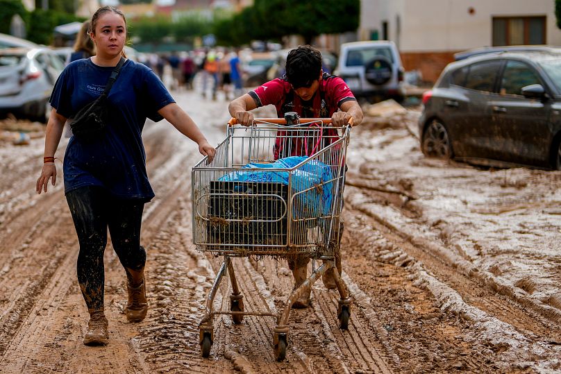 Two people push a cart loaded with belongings in Valencia, Spain, Thursday, Oct. 31, 2024. 