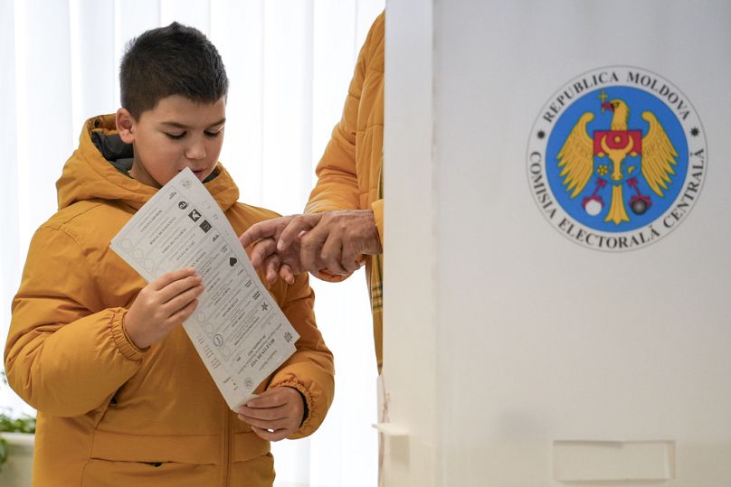 Bir çocuk ailesiyle birlikte oy kullanma merkezinde.