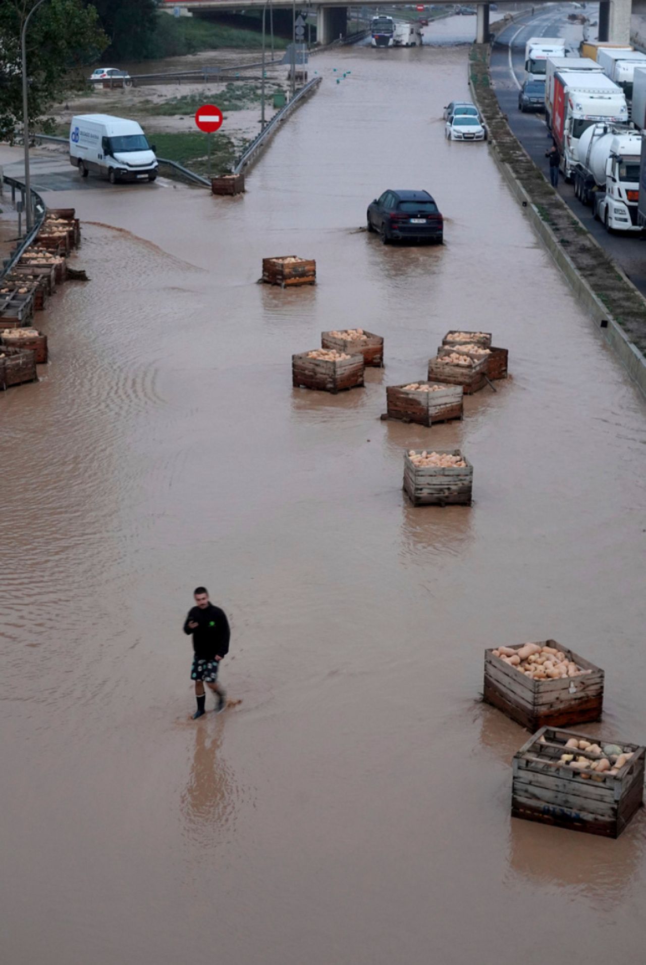 Un homme marche le lond d'une autoroute inondée à Valence.