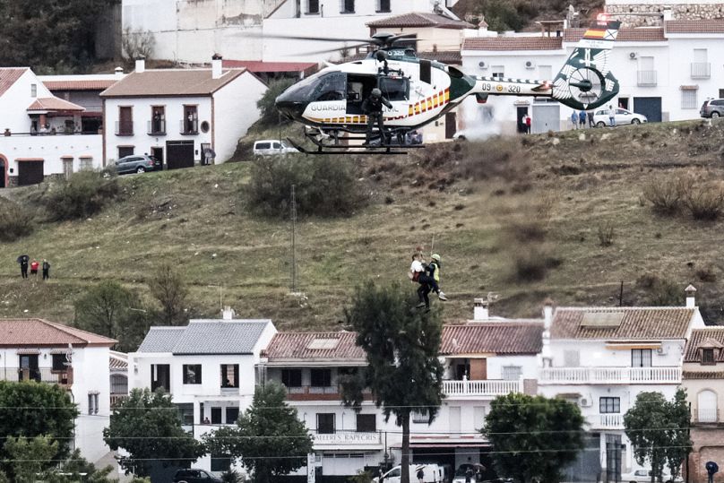 Equipos de emergencia rescatan a una persona que quedó varada por el agua en un helicóptero de la Guardia Civil.