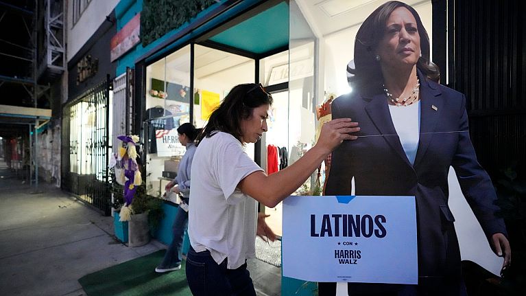 Emiliana Guereca, founder and president of the Women's March Foundation, adjusts a placard with the image of Democratic presidential nominee Vice President Kamala Harris.