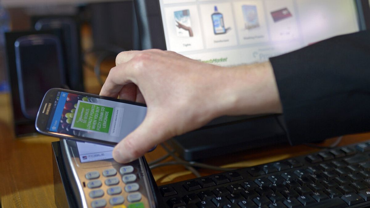 A man uses a mobile device for payment at the Mobile World Congress, the world's largest mobile phone trade show in Barcelona, Spain, Wednesday, Feb. 26, 2014.