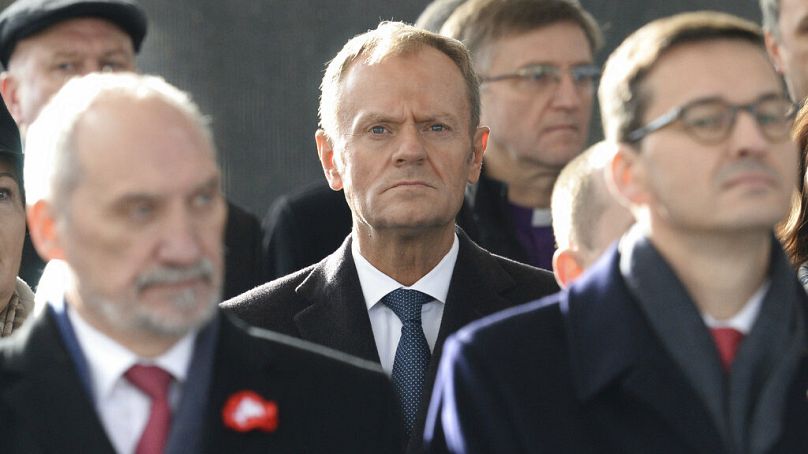 Donald Tusk (centre) stands behind Antoni Macierewicz (left) at a memorial