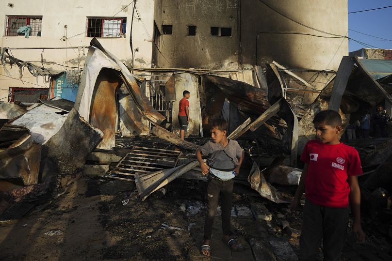 فلسطينيون ينظرون إلى الأضرار الناجمة عن غارة إسرائيلية أصابت خيمة في باحة مستشفى شهداء الأقصى في دير البلح بقطاع غزة، الاثنين 14 أكتوبر/تشرين الأول 2024