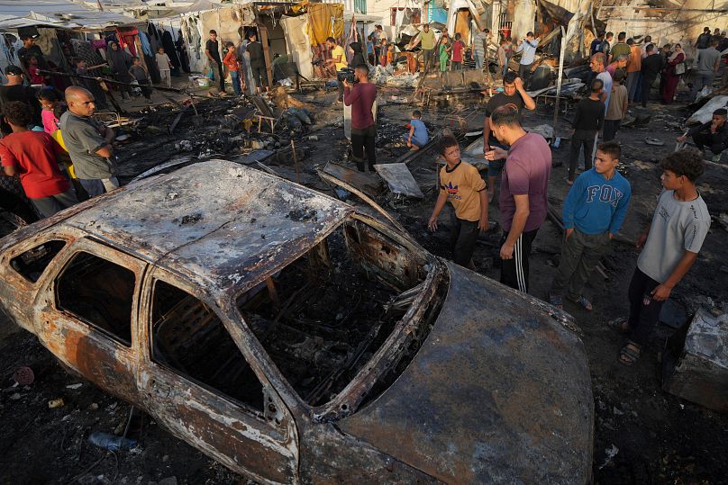 فلسطينيون ينظرون إلى الأضرار الناجمة عن غارة إسرائيلية أصابت خيمة في باحة مستشفى شهداء الأقصى في دير البلح بقطاع غزة، الاثنين 14 أكتوبر/تشرين الأول 2024