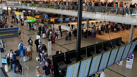 Travelers wait in long lines to check in and board flights at Amsterdam's Schiphol Airport, Netherlands, Tuesday, June 21, 2022.