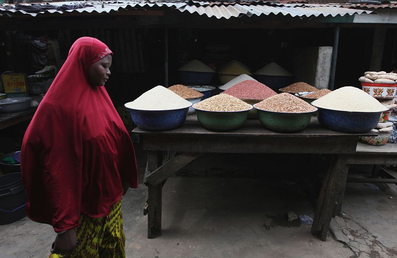 امرأة تسير بجانب مجموعة من المواد الغذائية المعروضة في سوق بمدينة لاغوس، نيجيريا