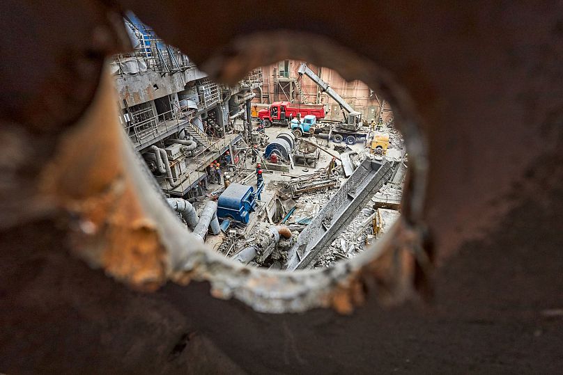 Vista a través de un agujero de metralla, los ingenieros devuelven la vida a una central eléctrica dañada.