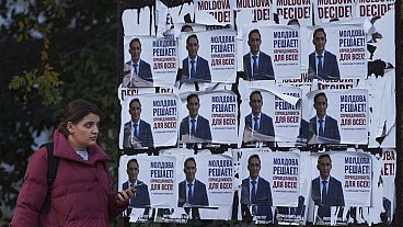 A woman walks past posters displaying Alexandr Stoianoglo, presidential candidate of the Socialists' Party of Moldova (PSRM) in Chisinau, Moldova, Friday Nov. 1, 2024. 