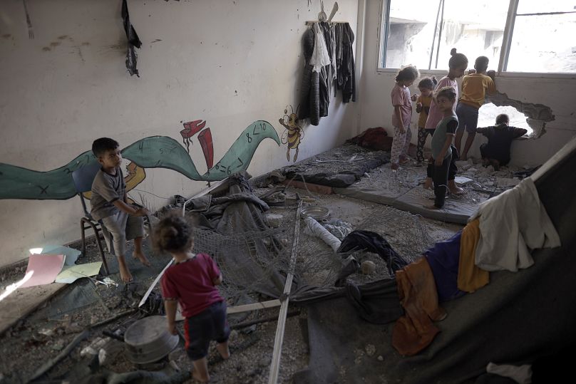 أطفال فلسطينيون يتنقلون في مدرسة تابعة للأونروا تأوي نازحين بعد يوم من استهداف منزل قريب بقصف إسرائيلي في خان يونس، جنوب قطاع غزة، الجمعة 21 يونيو 2024