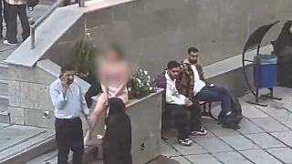 Un frame del video che mostra la studentessa senza vestiti affiancata da due guardie di sicurezza