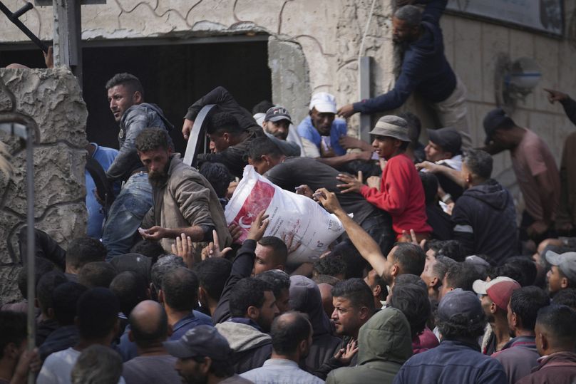 فلسطينيون يتجمعون لاستلام أكياس الطحين التي وزعتها الأونروا، وكالة الأمم المتحدة لمساعدة اللاجئين الفلسطينيين، في دير البلح، وسط قطاع غزة، السبت، 2 نوفمبر، 2024. 
