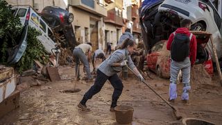 Persone puliscono la strada dal fango in un'area colpita dalle alluvioni a Paiporta, 2 novembre 2024