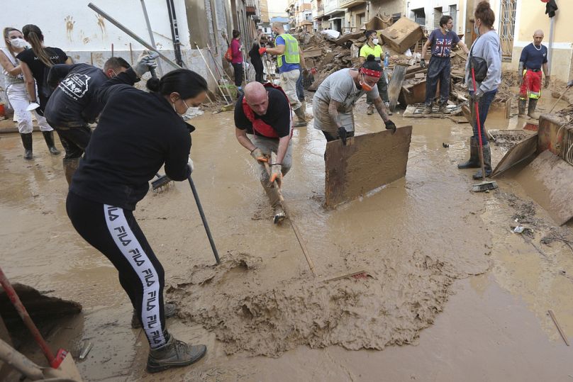 Residents and volunteers sweep away mud after floods in Paiporta, near Valencia, Spain, Sunday, Nov. 3, 2024.