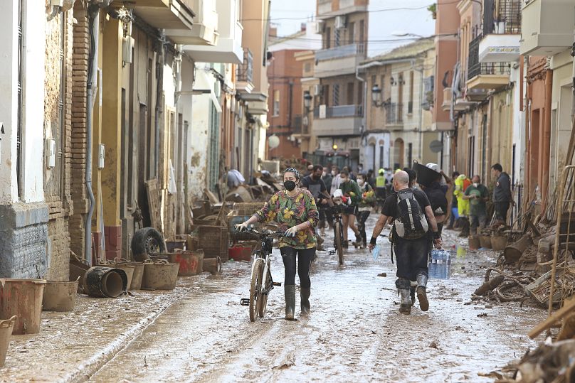 امرأة تدفع دراجة هوائية على طول شارع موحل بعد الفيضانات في بلدة بايبرتا، بالقرب من فالنسيا، إسبانيا، الأحد، 3 نوفمبر/تشرين الثاني 2024