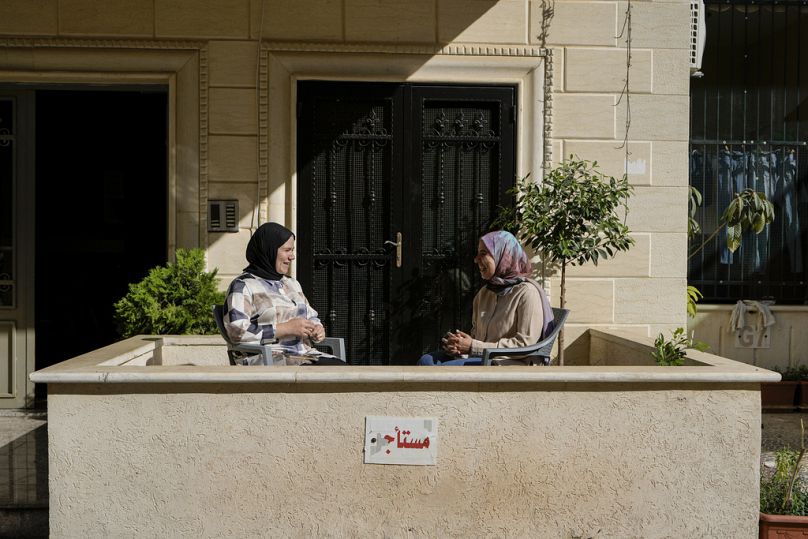 فاطمة جابر على اليمين وزينب على اليسار أثناء جلوسهما عند مدخل منزلهما في قرية عرمون جنوب شرق بيروت