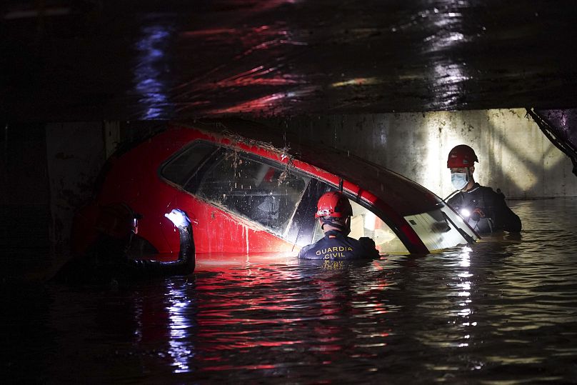 Civil Guards walk in a flooded indoor car park to check cars for bodies after floods in Paiporta, near Valencia, Spain, Monday, Nov. 4, 2024.