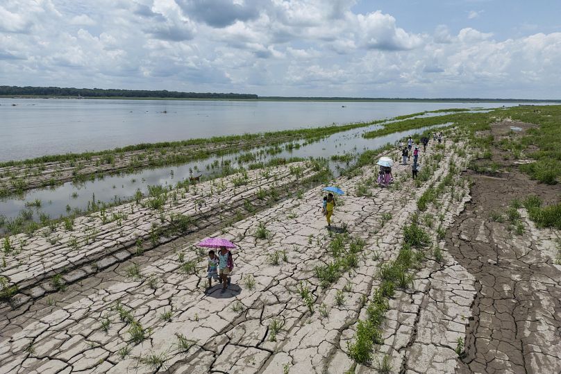 Des personnes marchent dans une partie du fleuve Amazone qui montre des signes de sécheresse à Santa Sofia, à la périphérie de Leticia, en Colombie, le 20 octobre 2024.
