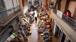 Persone camminano in una strada con mobili e rifiuti ammassati ai lati in un'area colpita dalle inondazioni a Paiporta, Valencia, Spagna, martedì 5 novembre 2024. 