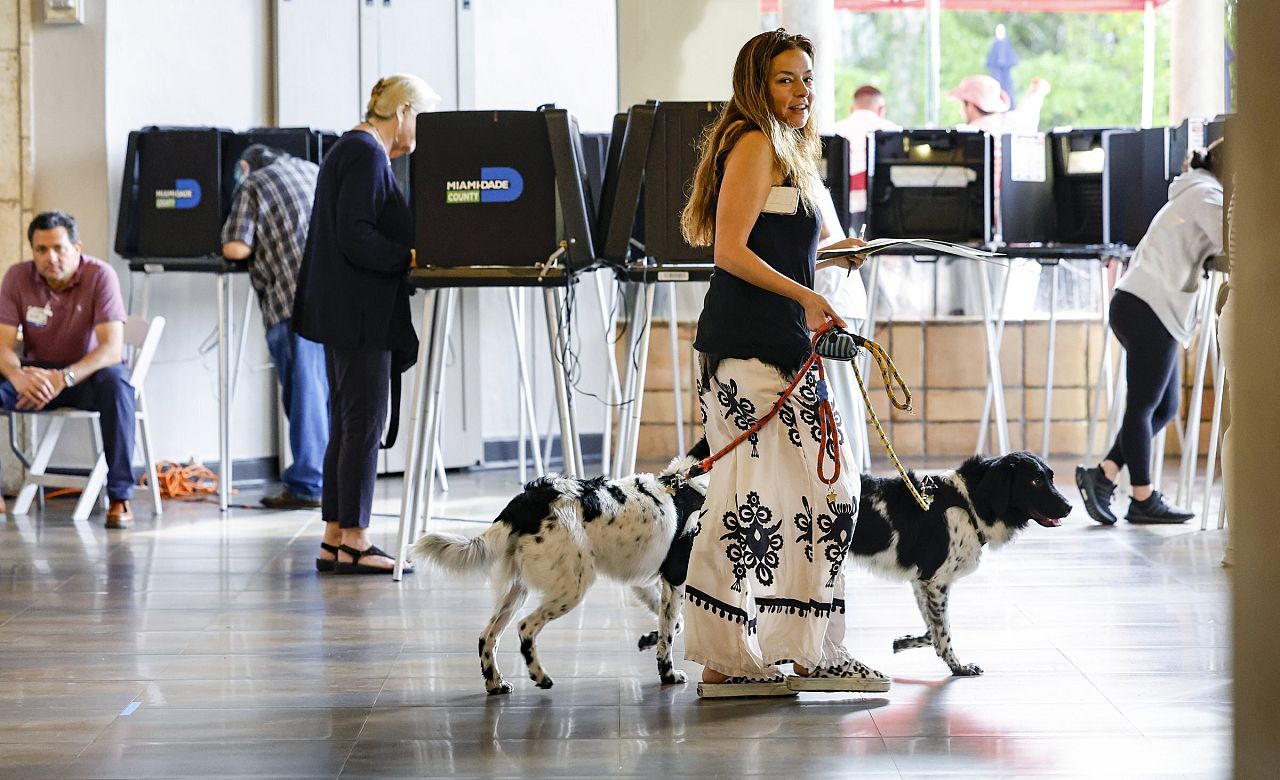 Eva Moore lleva su papeleta de voto con sus perros de servicio Apollo y Vinkenoog en el Coral Gables Country Club, Florida. 5 de noviembre de 2024.