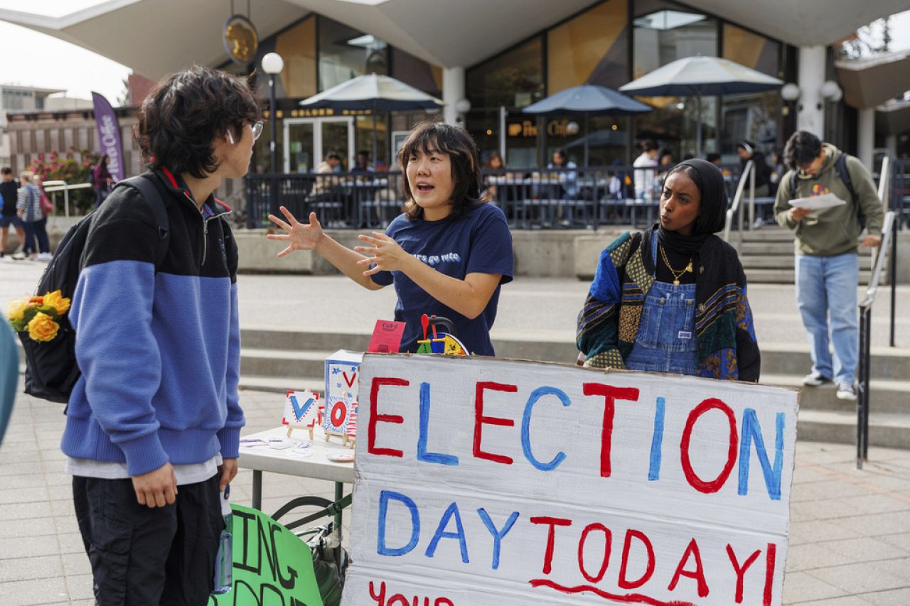 Renaissance Zhang, center, talks to a student about voting in Sproul Plaza at UC Berkeley on Election Day