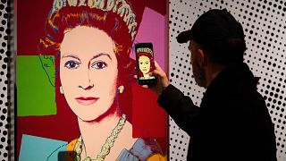 A man photographs an Andy Warhol screen print of Queen Elizabeth II, part of the 1985 "Reigning Queens" series, at Paleis Het Loo Museum in Apeldoorn, Netherlands.