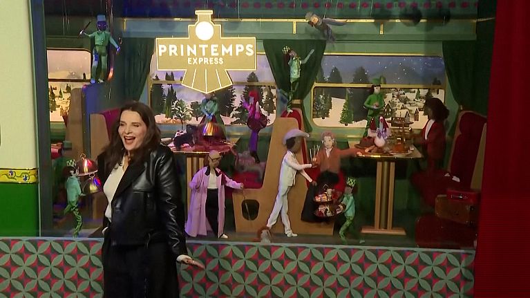 Juliette Binoche posing in front of the Christmas window