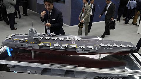 A visitor watches a replica of the the French new generation aircraft carrier during the Euronaval weapons show, Monday, Nov. 4, 2024 in Paris. 