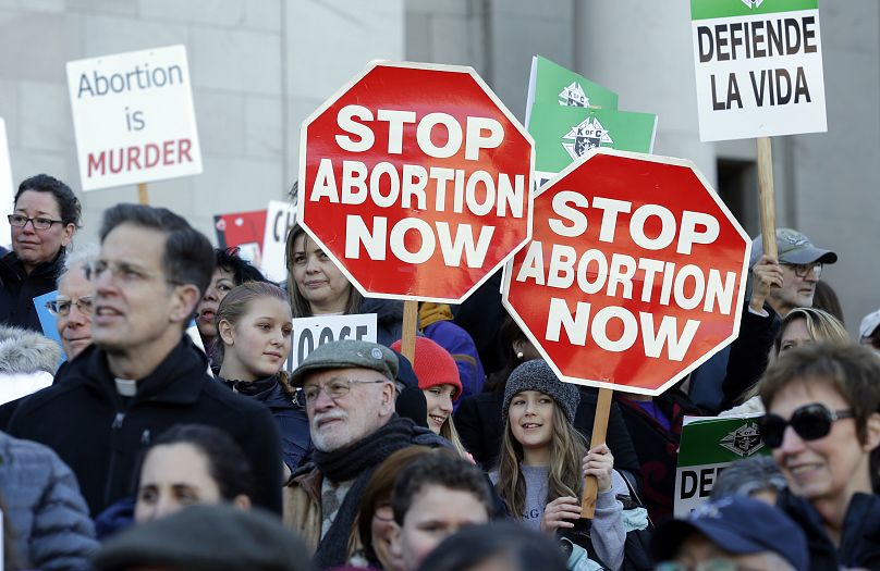 Participants in an anti-abortion rally hold signs that read "Stop Abortion Now" as they listen to speakers, Monday, Jan. 23, 2017