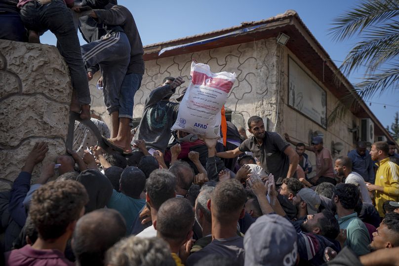 Palestinianos reúnem-se para receber sacos de farinha distribuídos pela UNRWA em Deir al Balah, 2 de novembro de 2024