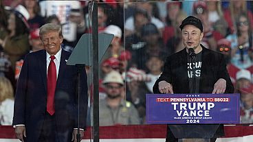 Republican presidential nominee former President Donald Trump listens as Elon Musk speaks during a campaign rally at the Butler Farm Show, Saturday, Oct. 5, 2024, in Butler, P