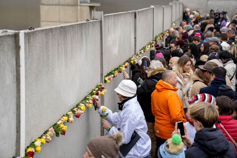 People attend a flower laying ceremony on occasion of the 35th wall anniversary at the grounds of the Berlin Wall Memorial, Berlin, Germany, Saturday, Nov.9, 2024. (AP Photo)