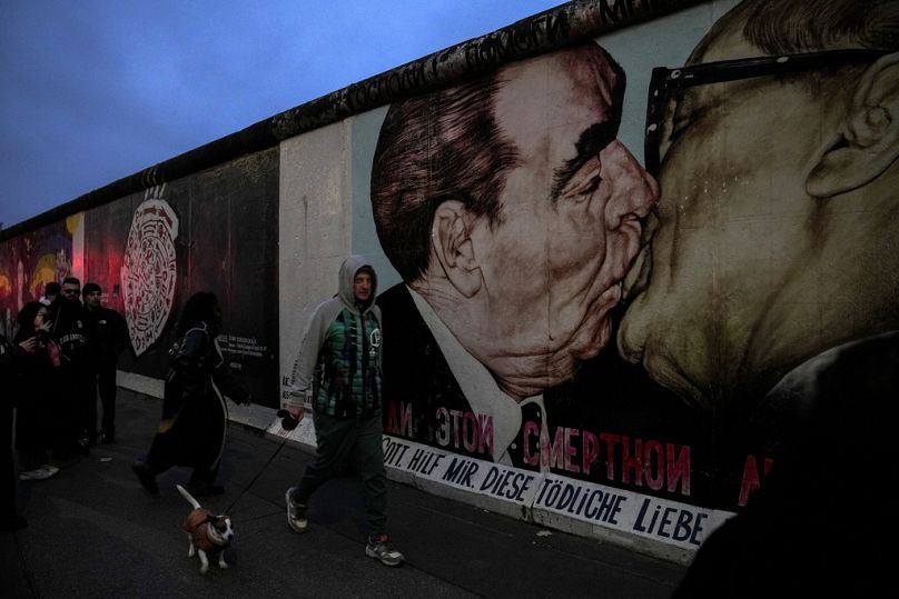 People walk past the so called East Side Gallery, a popular place for street art on remains of the Berlin Wall in Berlin, Germany, Friday, Nov. 8, 2024. (AP Photo)