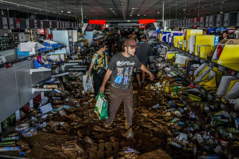 People pick up goods in a supermarket affected by the floods in Valencia, Spain, Thursday, Oct. 31, 2024. (AP Photo/Manu Fernandez)