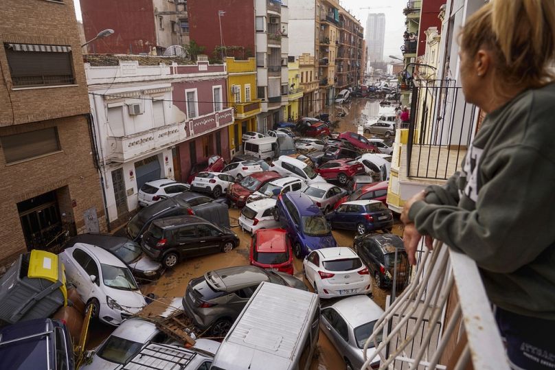 A woman looks out from her balcony as vehicles are trapped in the street during flooding in Valencia, Wednesday, Oct. 30, 2024. (AP Photo/Alberto Saiz)