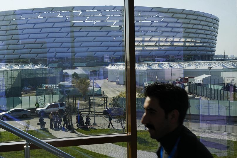 Des personnes marchent devant le stade olympique de Bakou, où se tient le sommet de l'ONU sur le climat COP29, le dimanche 10 novembre 2024, à Bakou, en Azerbaïdjan.