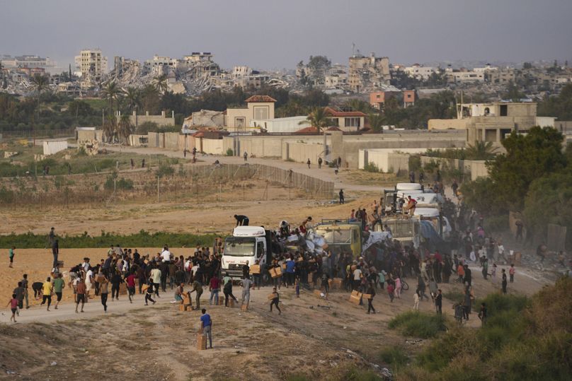 فلسطينيون يقتحمون شاحنات محملة بالمساعدات الإنسانية التي تم جلبها عبر رصيف جديد بنته الولايات المتحدة، في وسط قطاع غزة، في 18 مايو، 2024.