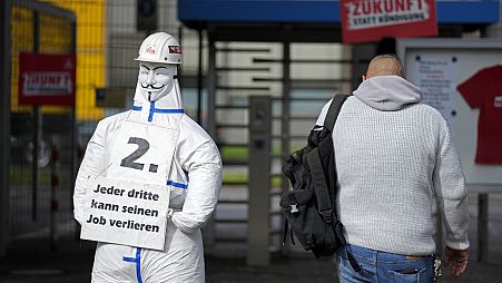 A worker enters the thyssenkrupp steelworks in Duisburg, Germany, Tuesday, Oct. 8, 2024, beside a sign of the steel union IG Metall reading "every third can lose his job"