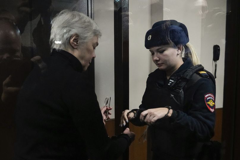 A police officer removes handcuffs form hands of Pediatrician Nadezhda Buyanova, accused of spreading false information about the army, prior to a hearing.