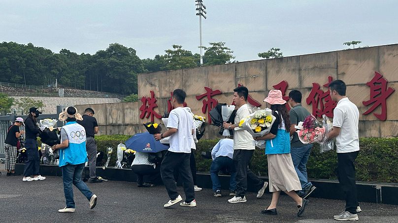 Voluntários recolocam as flores colocadas no exterior da “Zhuhai People's Fitness Plaza” na quarta-feira, 13 de novembro de 2024.