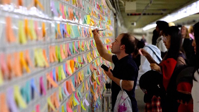 A commuter places a sticky note on the "Subway Therapy" wall, in New York.