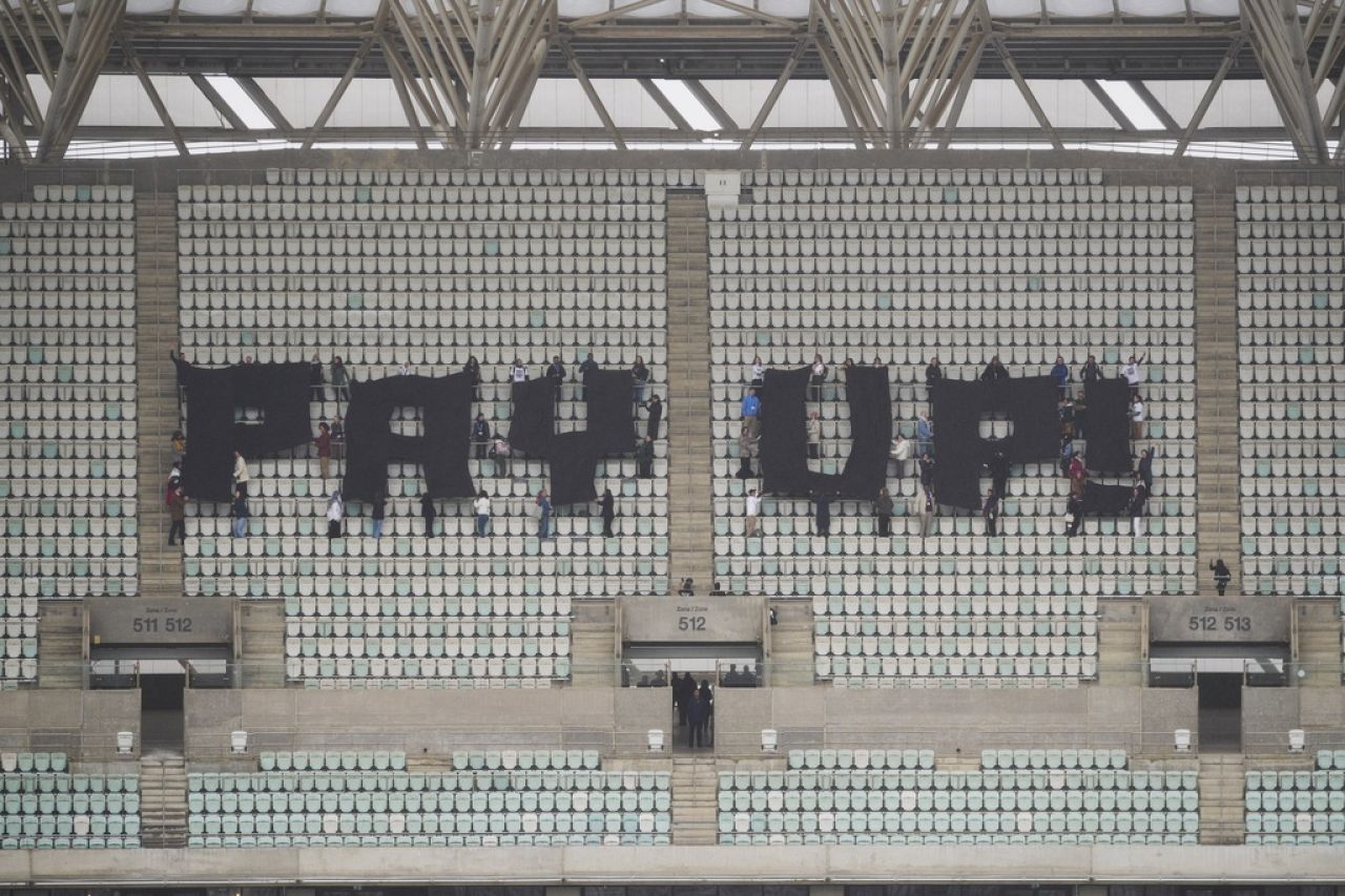 Activists with signs spell out "pay up" for climate finance in the Baku Olympic Stadium.